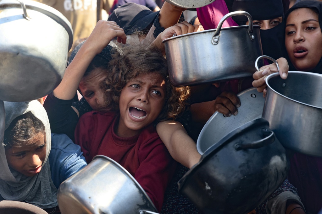 أطفال فلسطينيون في انتظار المساعدات أمام أحد المراكز في خان يونس جنوب قطاع غزة في 21 آب/أغسطس 2025 (أ ف ب)