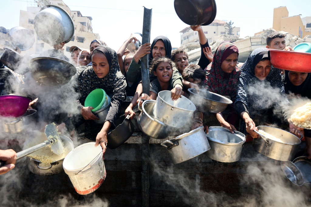 فلسطينيات يحاولن الحصول على كميات من الغذاء في تكية في مدينة غزة في 23 آب/أغسطس 2025 (أ ف ب)