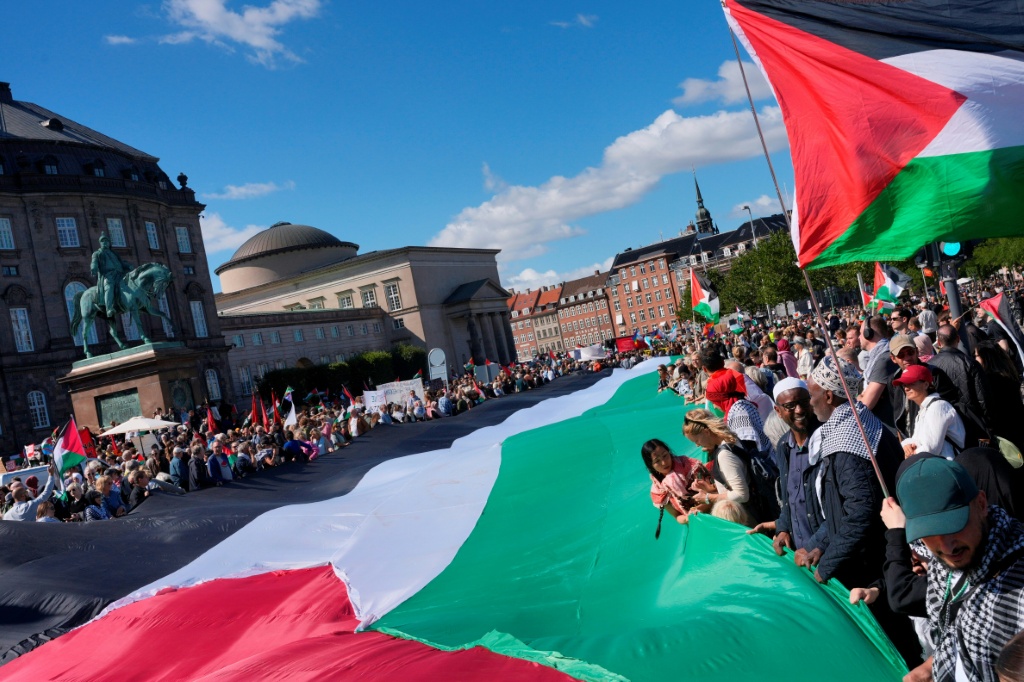 متظاهرون يرفعون علما فلسطينيا كبيرا خلال تظاهرة تحت شعار "كل الدنمارك في الشوارع من أجل فلسطين حرّة" في ساحة قصر كريستيانسبورغ في كوبنهاغن في 24 آب/أغسطس 2025 (أ ف ب)