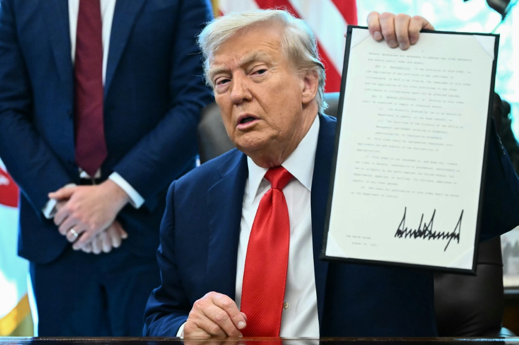 الرئيس الأميركي دونالد ترامب يحمل أمرا تنفيذيا وقعه في المكتب البيضوي بالبيت الأبيض في واشنطن العاصمة في 25 آب/أغسطس 2025 (أ ف ب)