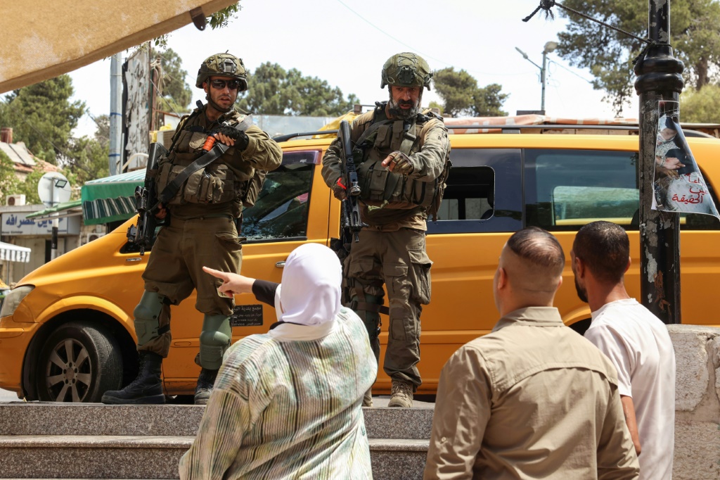 فلسطينيون وعنصران من القوات الإسرائيلية خلال المداهمة في مدينة رام الله في الضفة الغربية المحتلة في 26 آب/أغسطس 2025 (أ ف ب)