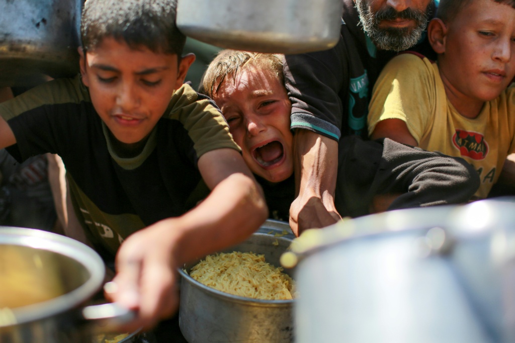أطفال يحاولون الحصول على الأرز من مطبخ خيري غرب مدينة غزة، في 28 آب/أغسطس 2025، بعد أن أعلنت الأمم المتحدة المجاعة في محافظة غزة الأسبوع الماضي (أ ف ب)