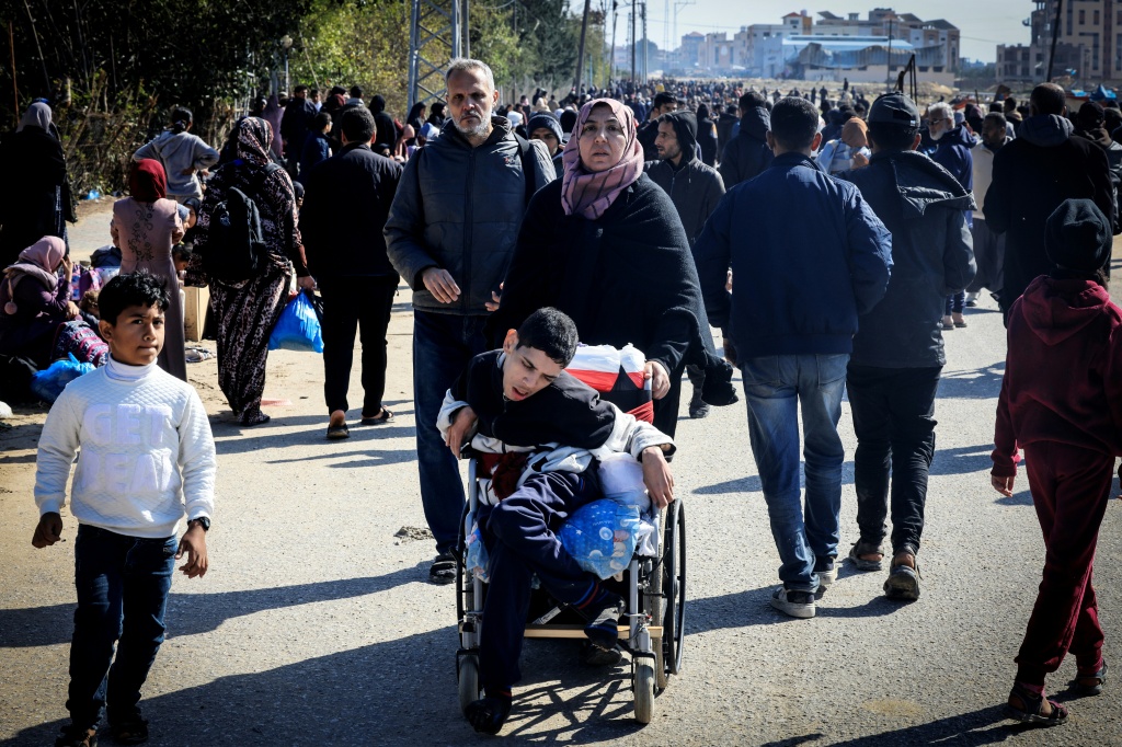 امرأة تدفع فتى يعاني من إعاقة أثناء فرار فلسطينيين من خان يونس إلى أماكن أكثر أمانا في جنوب قطاع غزة بتاريخ 26 كانون الثاني/يناير 2024 (أ ف ب)