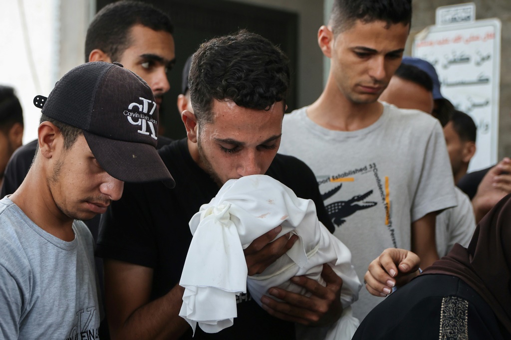 فلسطيني يقبل جثمان طفل مكفن خارج مستشفى الشفاء في مدينة غزة وكان الطفل قُتل في إحدى الغارات الإسرائيلية على مدينة غزة فجر الخميس الرابع من أيلول/سبتمبر 2025 (أ ف ب)