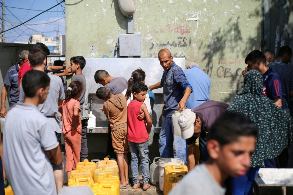 فلسطينيون ينتظرون تعبئة المياه في موقع لتوزيع المساعدات في مخيم النصيرات بقطاع غزة في الرابع من ايلول/سبتمبر 2025 (أ ف ب)