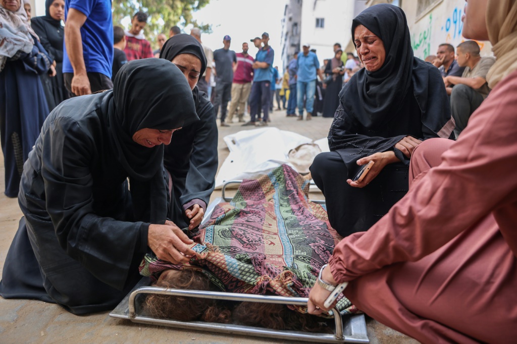 أقارب في مستشفى الشفاء في مدينة غزة، يبكون قرب جثتي طفلتين قتلتا في قصف إسرائيلي على خيمة نازحين وفق الدفاع المدني في القطاع، في الثامن من أيلول/سبتمبر 2025 (أ ف ب)