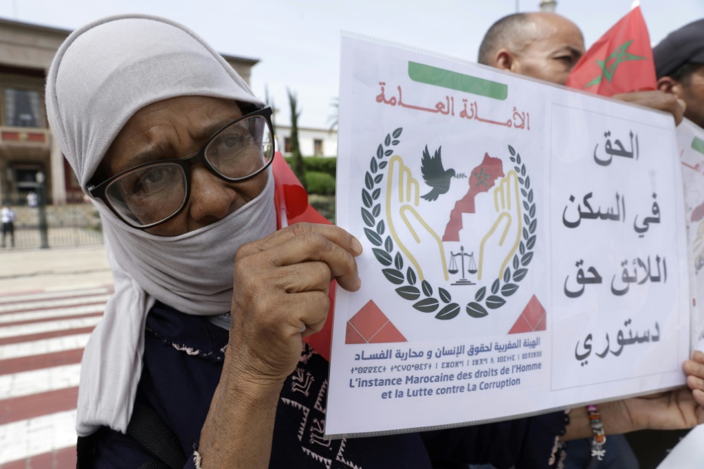 مغربية تحمل لافتة تنادي بالحق في السكن خلال تظاهرة للمطالبة بمساعدات حكومية لإعادة الاعمار في الرباط في الثامن من أيلول/سبتمبر 2025 (ا ف ب)
