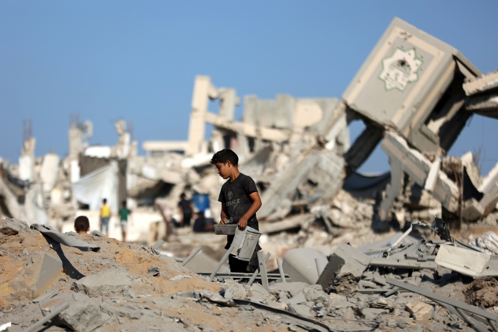 طفل فلسطيني نازح يقف وسط أنقاض مبنى دمرته غارة إسرائيلية ليلية في حي الرمال في مدينة غزة في 13أيلول/سبتمبر 2025 (أ ف ب)