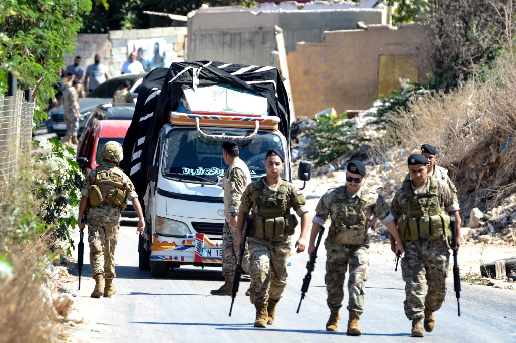 جنود من الجيش اللبناني وخلفهم شاحنة محمّلة بالأسلحة تغادر مخيم البدّاوي للاجئين الفلسطينيين، قرب مدينة طرابلس شمالي لبنان، في 13 أيلول/سبتمبر 2025 (أ ف ب)