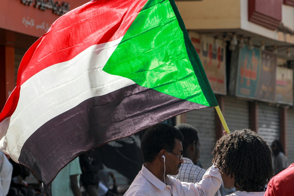 رجل يلوح بالعلم الوطني السوداني في العاصمة الخرطوم في 24 كانون الثاني/يناير 2023 (أ ف ب)