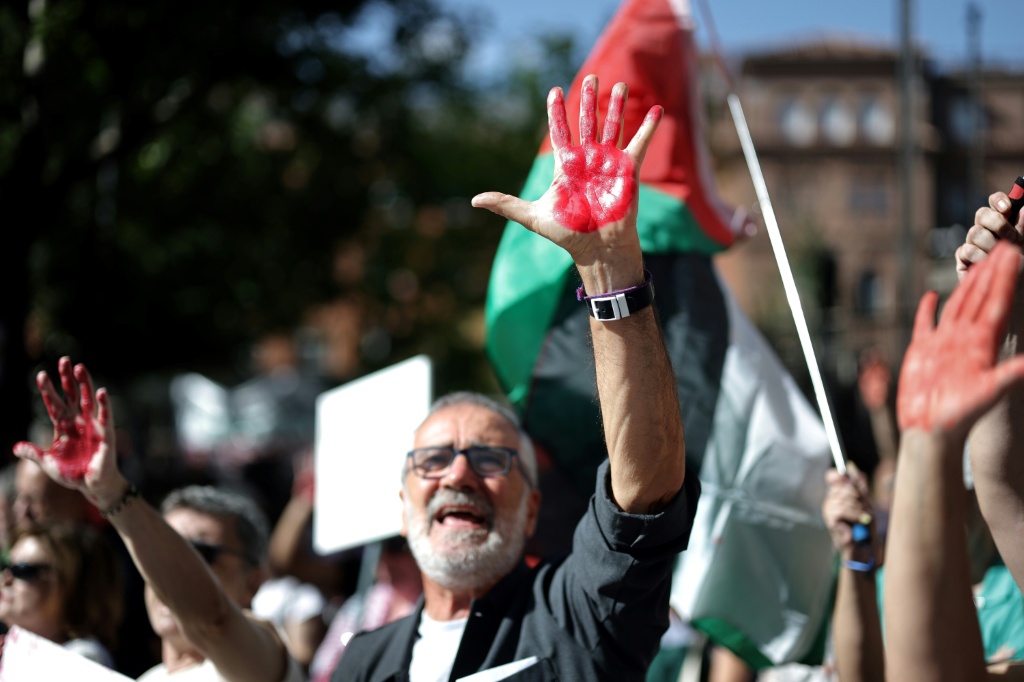 متظاهرون أيديهم ملطخة باللون الأحمر خلال مظاهرة مؤيدة للفلسطينيين أمام السفارة الإسرائيلية في مدريد، في 6 أيلول/سبتمبر 2025 (ا ف ب)