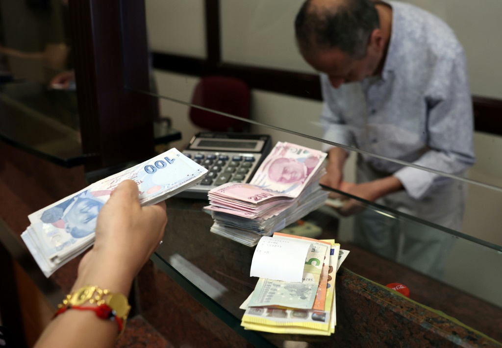 زبونة تبدّل مبلغا بالليرة التركية بما يوازيه بالدولار عند صرّاف في أنقرة في 20 تموز/يوليو 2023 (أ ف ب)