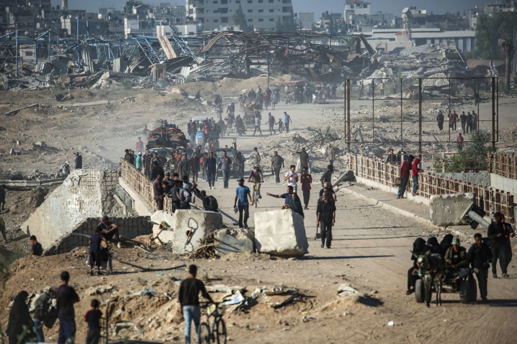 فلسطينيون يسيرون على طول الطريق الساحلي في وسط قطاع غزة باتجاه مدينة غزة شمالا في 11 تشرين الأول/أكتوبر 2025 (أ ف ب)