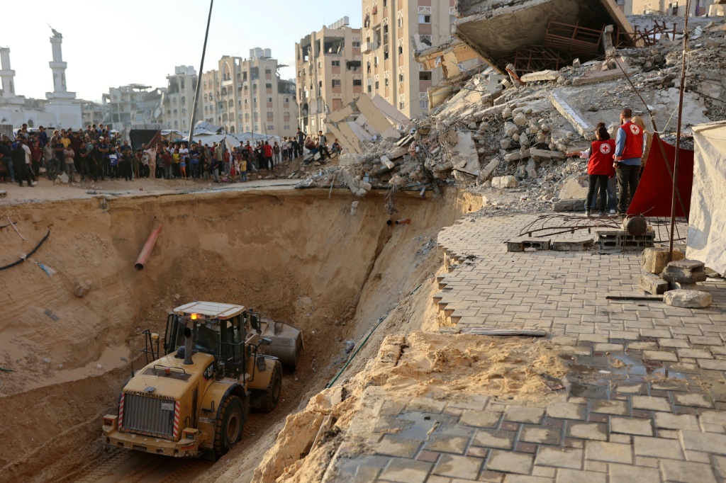 سكان وعناصر من الصليب الأحمر يراقبون عملية حفر للبحث عن جثث رهائن في خان يونس جنوب قطاع غزة في 17 تشرين الأول/أكتوبر 2025 (ا ف ب)