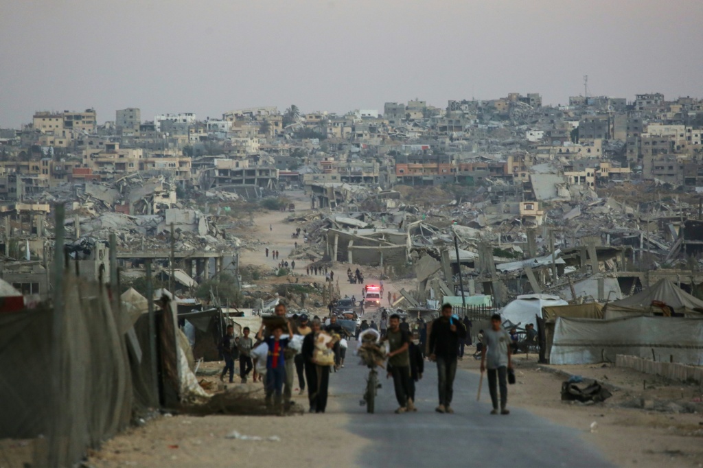 لقطةأشخاص في شارع حيث تبدو خلفهم المباني المدمّرة في خان يونس بتاريخ 25 تشرين الأول/أكتوبر 2025 (ا ف ب)