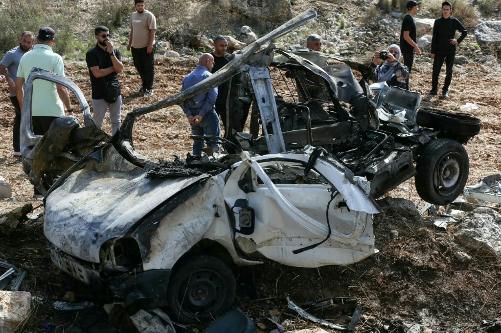 يعاينون حطام سيارة استهدفتها غارة اسرائيلية في بلدة حاروف بجنوب لبنان في 25 تشرين الاول/اكتوبر 2025 (ا ف ب)