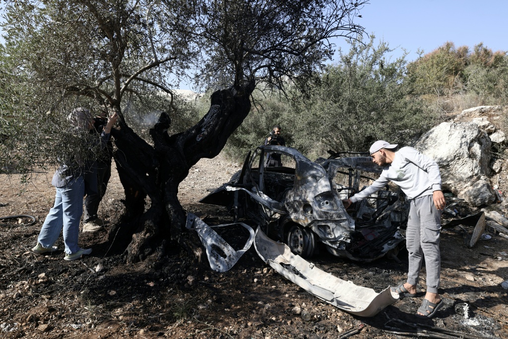 فلسطينيون يتفقّدون بقايا سيارة محطمة في موقع مقتل 3 شبان فلسطينيين بنيران جيش الاحتلال الإسرائيلي أثناء غارة على قرية كفر قود قرب مدينة جنين شمال الضفة الغربية المحتلة في 28 تشرين الأول/أكتوبر 2025. (ا ف ب)