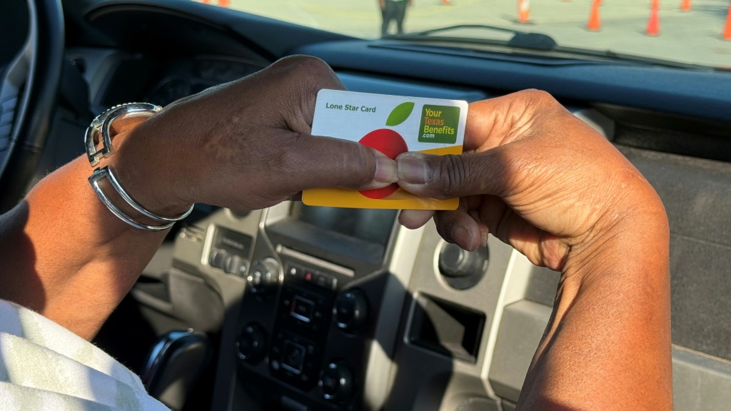 إحدى سكان هيوستن تحمل بطاقة هويتها كمستفيدة من برنامج المساعدات الغذائية التكميلية أثناء انتظارها الحصول على سلع مجانية من برنامج بنك الطعام في هيوستن تكساس، في الأول من تشرين الثاني/نوفمبر 2025 (ا ف ب)