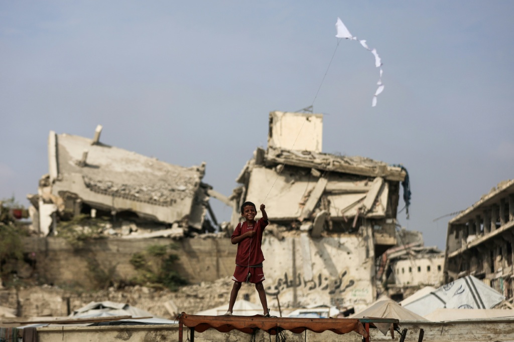طفل يطير بطائرة ورقية أمام المباني المدمرة في مدينة غزة في 3 تشرين الثاني/نوفمبر 2025، خلال وقف إطلاق النار في الحرب التي استمرت عامين بين إسرائيل وحماس (ا ف ب)