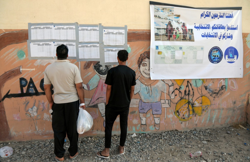 نازحان عراقيان يطّلعان على قوائم خلال التصويت المبكر في الانتخابات التشريعية العراقية في التاسع من تشرين الثاني/نوفمبر 2025 في مخيم الدباغة شرق قضاء مخمور بشمال العراق (ا ف ب)