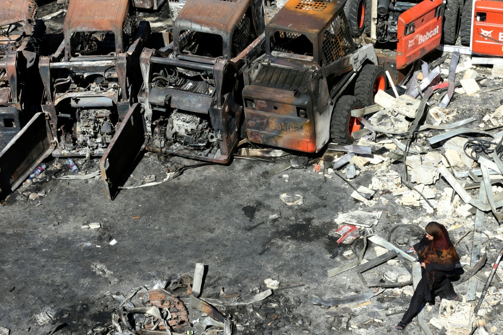 امرأة تسير أمام معدات زراعية متفحمة في قرية المصيلح اللبنانية بتاريخ 11 تشرين الأول/أكتوبر 2025 (ا ف ب)