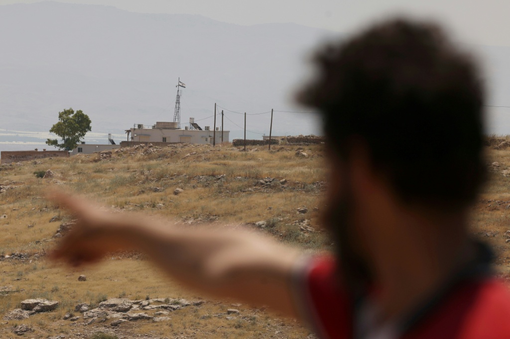 فلسطيني يشير إلى منزل مستوطن عليه العلم الإسرائيلي خارج قرية الجفتلك الفلسطينية في شمال أريحا بوسط الضفة الغربية المحتلة في 16 نيسان/أبريل 2024 (ا ف ب)