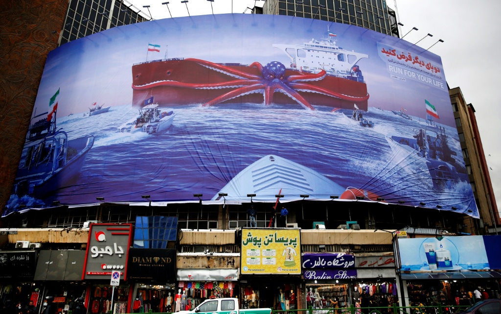 لافتة في طهران يعود تاريخها إلى 5 تشرين الثاني/نوفمبر 2021 تظهر وحدات بحرية تابعة للحرس الثوري الإيراني وهي تراقب سفينة حربية أميركية في خليج عمان (ا ف ب)
