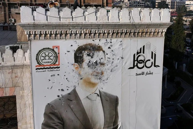 اطلاق الرصاص على صورة الرئيس السوري المخلوع بشار الأسد (أ ف ب)