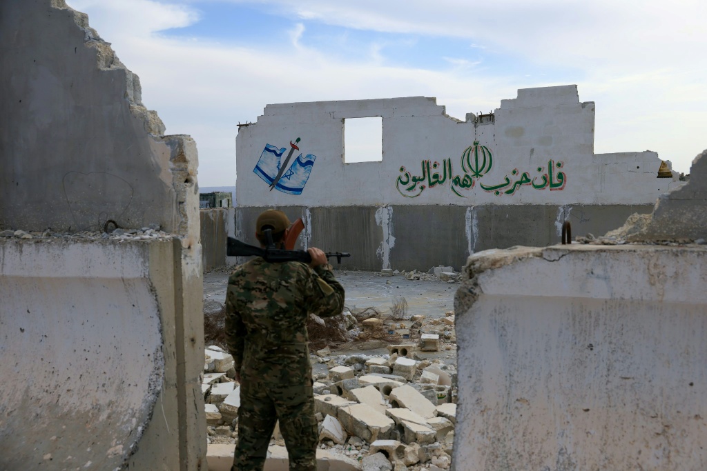 جندي في وزارة الدفاع السورية التابعة للسلطات الجديدة ينظر في الرابع من كانون الأول/ديسمبر 2025 إلى جدار متداع لما كانت أكبر قاعدة عسكرية إيرانية في سوريا، في حلب. (ا ف ب)