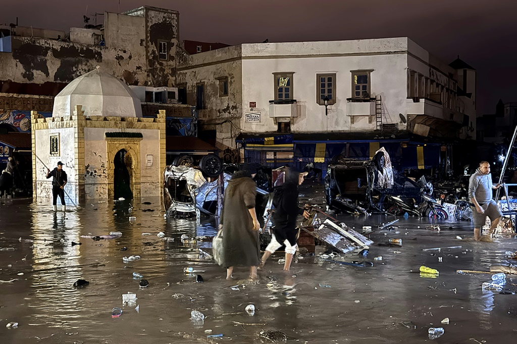 أشخاص يخوضون المياه في ساحة بعد فيضان مفاجئ في مدينة آسفي المغربية في 14 كانون الاول/ديسمبر 2025 (ا ف ب)