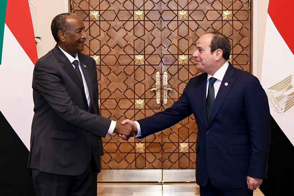 صورة وزعتها الرئاسة المصرية للرئيس المصري عبد الفتاح السيسي (يمين) وهو يصافح قائد الجيش السوداني عبد الفتاح البرهان في القاهرة بتاريخ 18 كانون الاول/ديسمبر 2025 (أ ف ب)