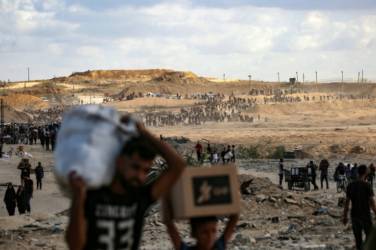 فلسطينيون يحملون أكياس مساعدات غذائية بعد خروجهم من مركز توزيع تابع لـ"مؤسسة غزة الإنسانية" في وسط قطاع غزة، في الخامس من تشرين الأول/أكتوبر 2025 (أ ف ب)