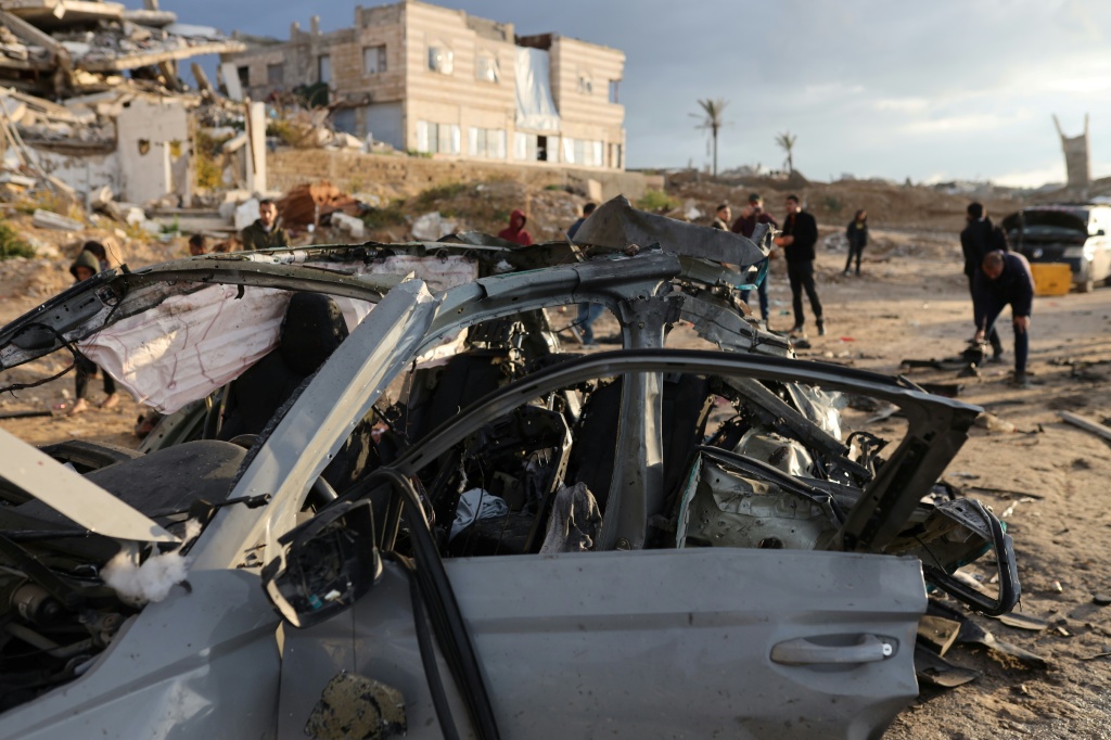 فلسطينيون يتفقدون أضرار غارة إسرائيلية على سيارة في مدينة غزة في 13 كانون الأول/ديسمبر 2025 (ا ف ب)
