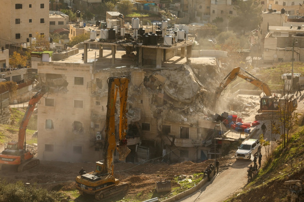 جرافات تابعة لبلدية القدس الإسرائيلية في القدس الشرقية تعمل على هدم مبنى مؤلف من أربع طوابق كانت تسكنه 12 عائلة فلسطينية بحجة البناء بدون ترخيص في 22 كانون الأول/ديسمبر 2025 (ا ف ب)