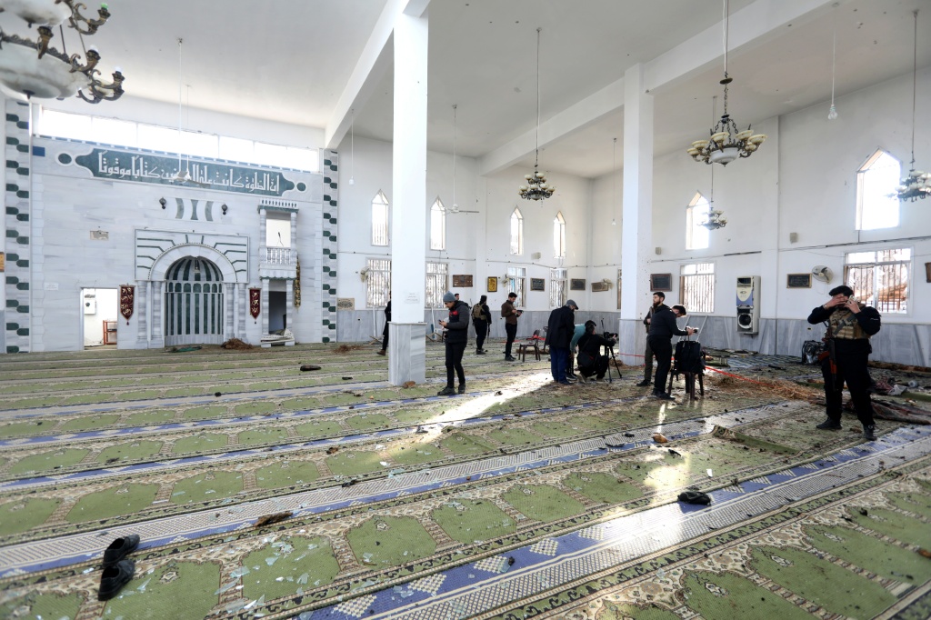 عناصر من الأمن وصحافيون في موقع الانفجار داخل مسجد الإمام علي بن أبي طالب في حي وادي الدهب بمدينة حمص في 26 كانون الأول/ديسمبر 2025 (ا ف ب)