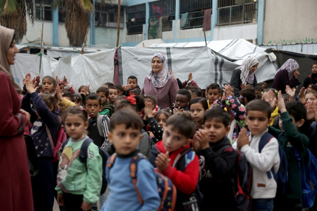 أطفال فلسطينيون، كثير منهم من عائلات نازحة، يتجمعون في ساحة مدرسة دير البلح المشتركة التابعة لوكالة الأونروا في وسط قطاع غزة في 6 كانون الأول/ديسمبر 2025 (ا ف ب)