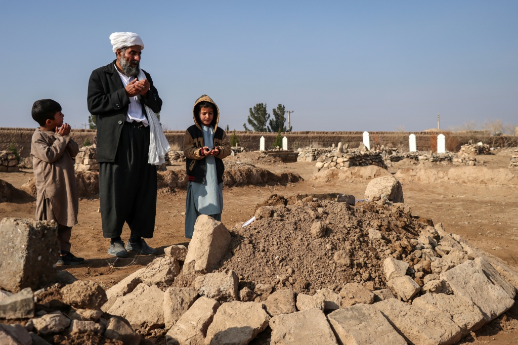 غول أحمد، في الوسط، وأقاربه يصلون عند قبر حبيب الله في قرية غنجان بأفغانستان، في 26 كانون الأول/ديسمبر 2025 (ا ف ب)