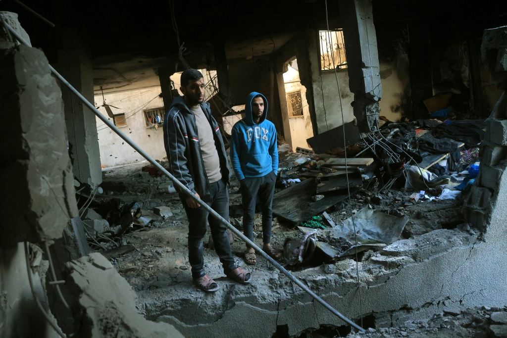فلسطينيان يتفقدان منزلا مدمّرا بعد غارة إسرائيلية في دير البلح في وسط قطاع غزة في 16 كانون الثاني/يناير 2026 (ا ف ب)