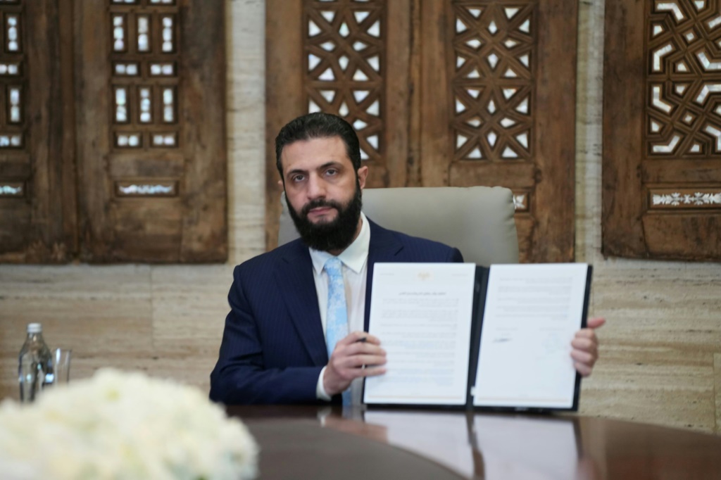 الرئيس السوري أحمد الشرع يرفع الاتفاق الموقع مع قوات سوريا الديموقراطية في 18 كانون الثاني/يناير 2026 (ا ف ب)
