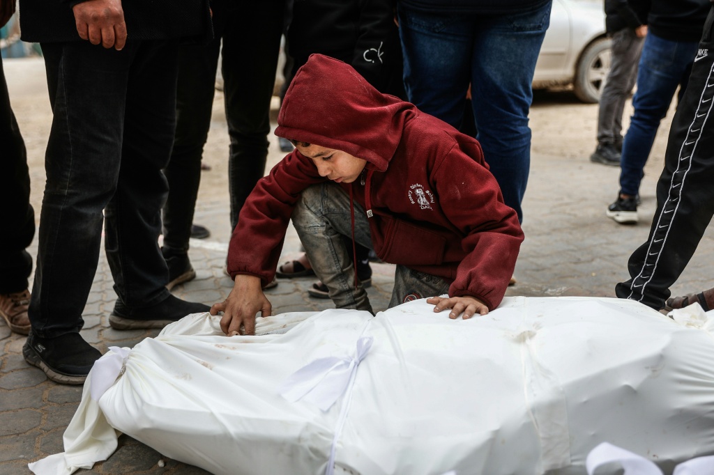طفل يتفقد جثمانا في مستشفى الشفاء بعد مقتل أربعة فلسطينيين أثناء جمعهم الحطب شرق حي الزيتون بمدينة غزة في 22 كانون الثاني/يناير 2026 (ا ف ب)