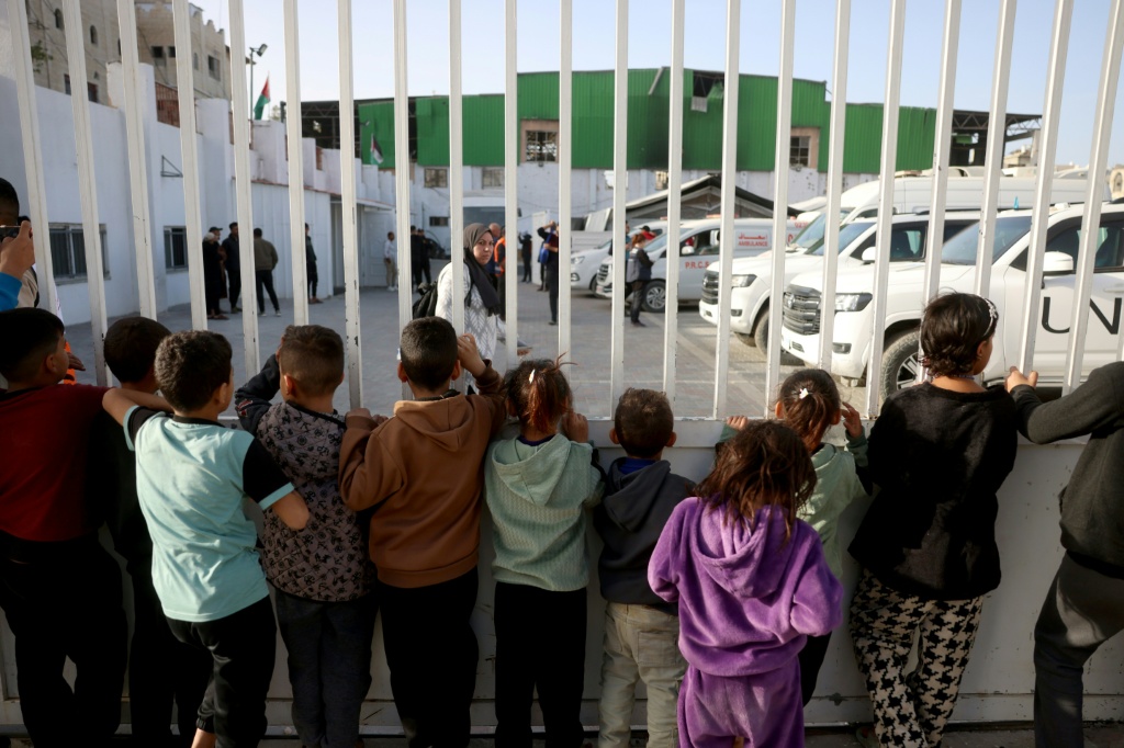 أطفال فلسطينيون يشاهدون جرحى حرب ومرضى آخرين يستعدون لمغادرة قطاع غزة لتلقي العلاج عبر معبر رفح الحدودي بين قطاع غزة ومصر بعد أن فتحته إسرائيل لعدد محدود من الأشخاص، في خان يونس جنوب قطاع غزة، في 8 شباط/فبراير 2026 (ا ف ب)