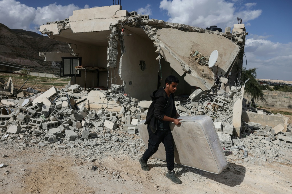 فلسطيني يحمل مرتبة أخرجها من بين أنقاض منزل قال سكانه إن مستوطنين إسرائيليين هدموه في قرية على مشارف أريحا، في الضفة الغربية المحتلة، في 11 شباط/فبراير 2026 (ا ف ب)