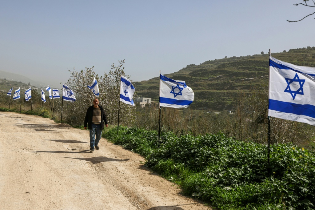 فلسطيني يسير بمحاذاة سياج نصب عليه مستوطنون إسرائيليون علم الاحتلال الإسرائيلي بعد إعلانهم في 15 شباط/فبراير، السيطرة على محطة قطار المسعودية التاريخية التي تعود لعهد الدولة العثمانية التي كانت تربط مدينتي نابلس وطولكرم في القرن الماضي (ا ف ب)
