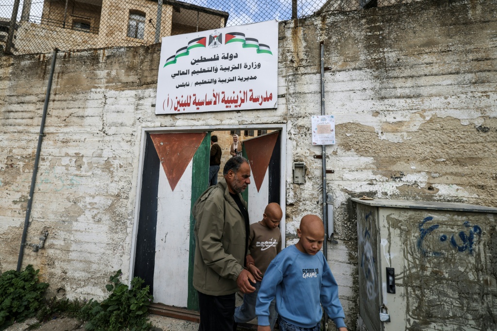 التلميذان التوأمان احمد ومحمد امام مدرستهما في نابلس بالضفة الغربية في العاشر من شباط/فبراير 2026 (ا ف ب)
