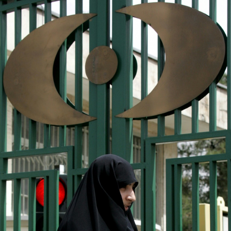 امرأة أمام بوابة تحمل رمز المنظمة الإيرانية للطاقة الذرية في طهران في 9 نيسان/أبريل 2007(ا ف ب)