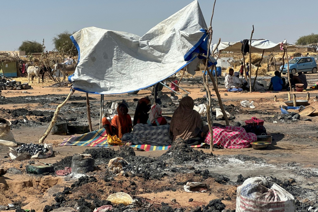 نازحون سودانيون فروا من الفاشر بعد سقوطها يجلسون في مخيم الطويلة في شمال السودان، وسط بقايا حريق اندلع في المخيم في 11 شباط/فبراير 2026 (ا ف ب)