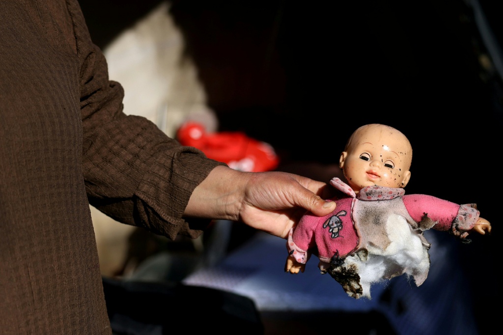امرأة فلسطينية تعرض دمية محترقة بعد أن أضرم مستوطنون إسرائيليون من مستوطنة مجاورة النار في خيمتها في قرية سوسيا في جنوب محافظة الخليل في الضفة الغربية المحتلة في 25 شباط/فبراير 2026 (ا ف ب)