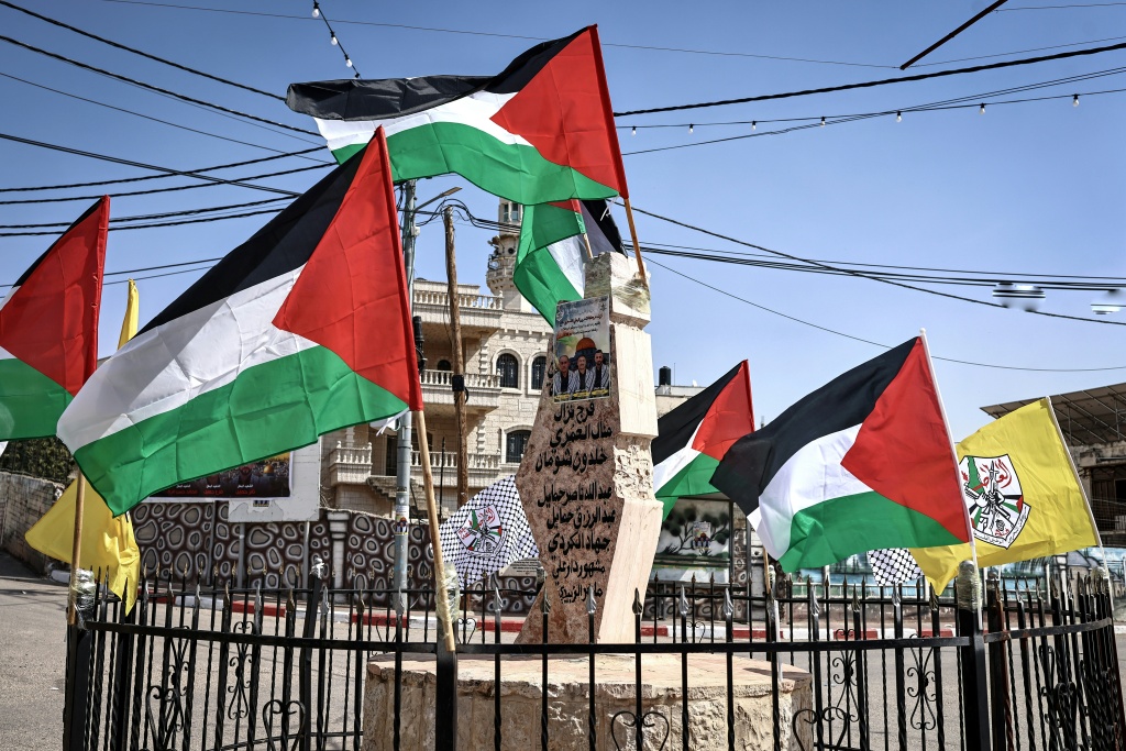 الأعلام الفلسطينية عند نصب يحمل أسماء الأشخاص الذين قتلوا بأيدي جيش الاحتلال الإسرائيلي أو مستوطنين في خربة أبو فلاح، شمال شرق رام الله، في الضفة الغربية المحتلة بتاريخ 12 آذار/مارس 2026 (ا ف ب)