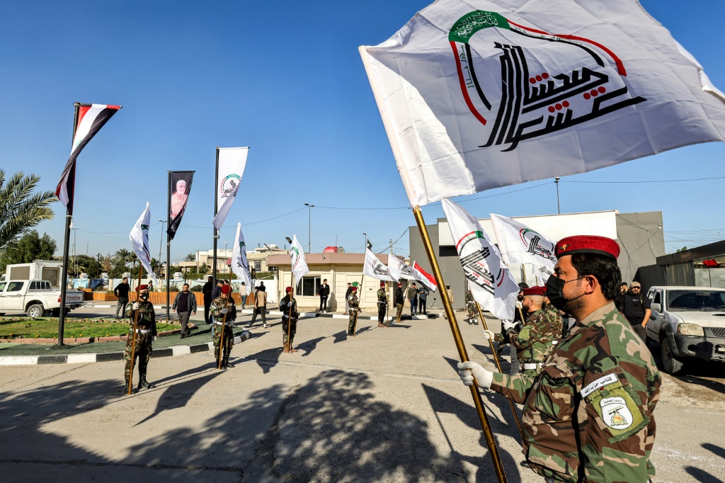 عناصر في هيئة الحشد الشعبي يحملون علم الهيئة في 26 كانون الأول/ديسمبر 2023 في بغداد خلال تشييع أحد عناصر فصيل كتائب حزب الله كان قد قُتل بضربة أميركية (ا ف ب)