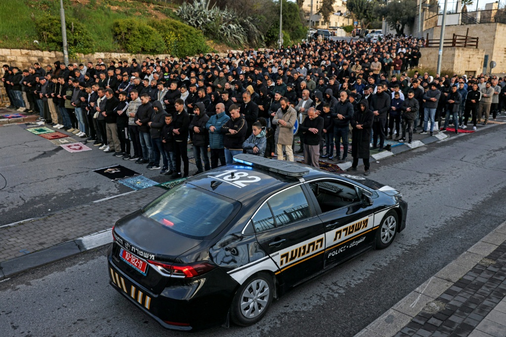 سيارة تابعة لشرطة الاحتلال الإسرائيلية تمر بجانب المصلين المتجمعين خارج أسوار البلدة القديمة في القدس في 20 آذار/مارس 2026 لأداء صلاة عيد الفطر (ا ف ب)